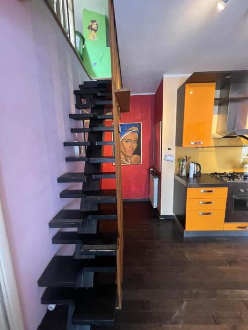 Black spiral staircase in Sofy Penthouse at Versilia Panoramic Luxury hotel, Como, with colorful kitchen