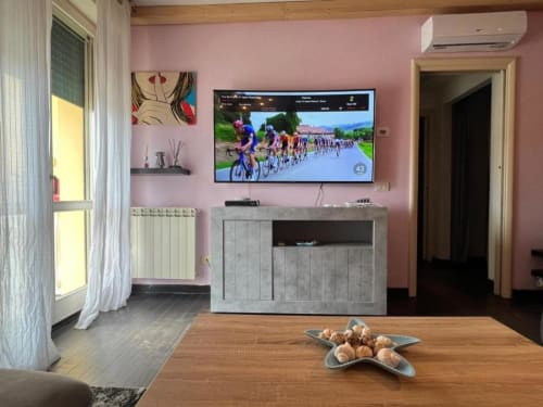 Modern pink living room at Versilia Panoramic Luxury with TV, wooden table, and contemporary furnishings