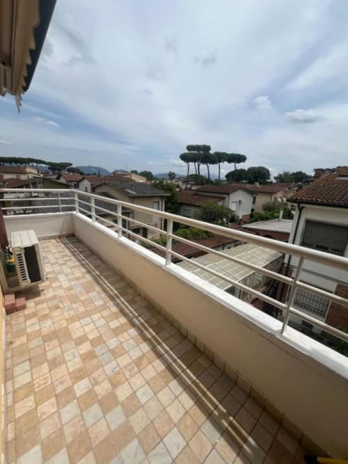Sofy Penthouse terrace at Versilia Panoramic Luxury in Como with tiled floor, white railing, and panoramic views of rooftops