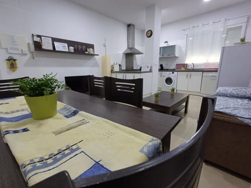 Modern kitchen-dining area in Algemesi Home apartment with dining table, black chairs, equipped kitchen, and city views