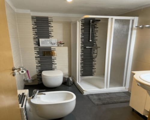 Modern bathroom at Algemesi Home with round basin sink, toilet, and walk-in shower with black tile accents