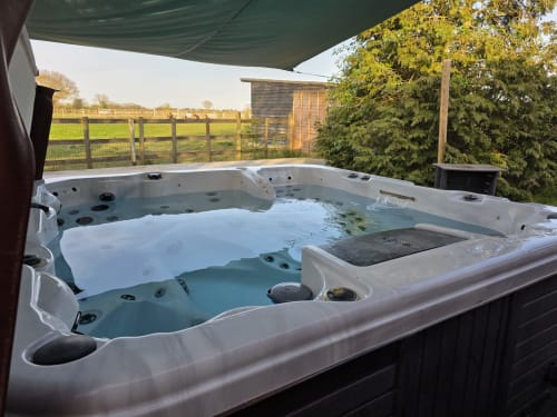 Luxurious hot tub on the garden patio of Maple Lodge cottage at Blackbrook Cottages, Colchester, with countryside views and