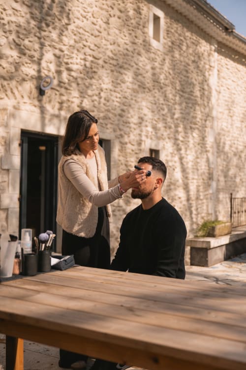 Maquilleuse appliquant des cosmétiques à une cliente sur la terrasse extérieure du Mas de la Vernède à Aramon