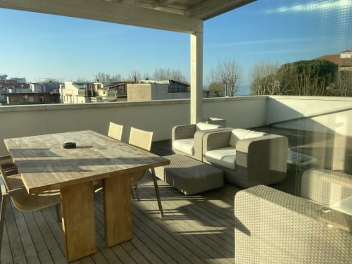 Spacious rooftop terrace at Rimini apartment with dining table, lounge chairs, and city views