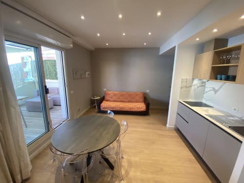 Modern studio apartment in Rimini with kitchenette, dining area, orange sofa, and balcony access