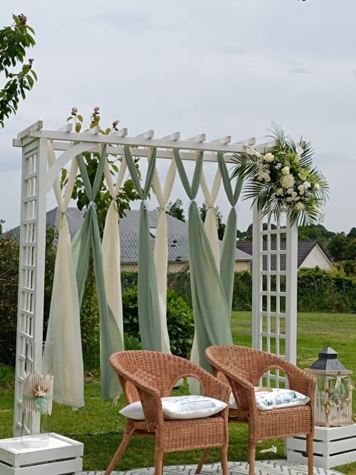 Pergola blanche avec tissus drapés et compositions florales au Domaine de la Marnière à Villainville