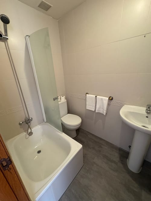 Baño limpio con bañera, ducha, inodoro y lavabo en el hotel Pensión Argüelles de Ribadesella