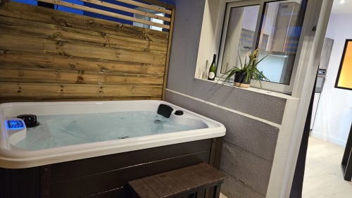 Luxueux jacuzzi de la Diamond'Suite loveroom&spa à la Résidence L'Hermitière, avec eau chauffée, tête de lit en bois