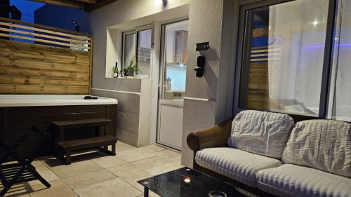 Salon moderne avec panneaux bois striés, canapé gris, cheminée et portes donnant sur le jardin à la Résidence
