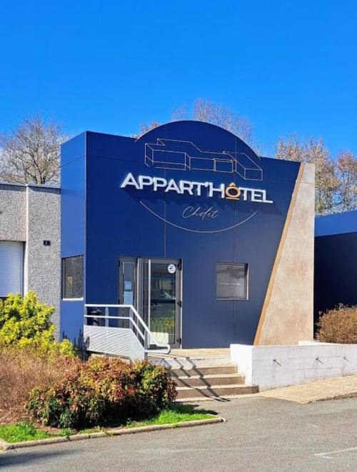 Entrée de l'Appart'Hôtel Cholet moderne avec façade bleue et architecture contemporaine