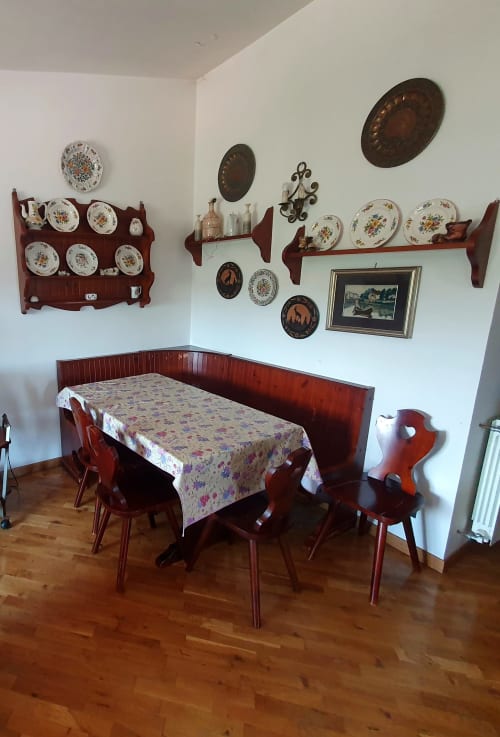 Sala da pranzo vintage nella Residenza Altipiani di Arcinazzo a Roma con mobili in legno rosso, tovaglia floreale e decorazioni