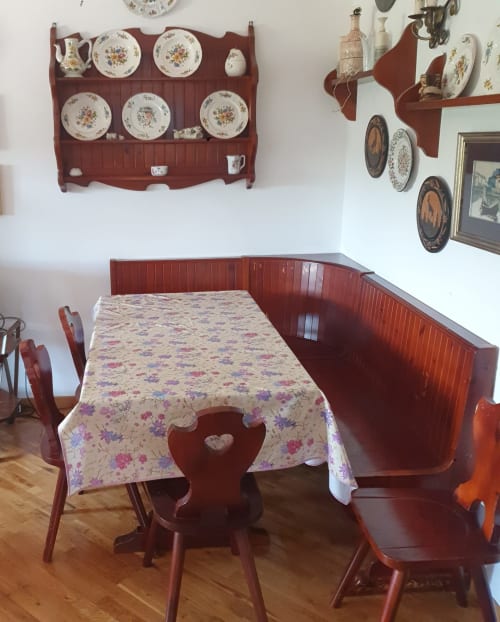 Sala da pranzo rustica con tavolo di legno rosso, tovaglia a fiori e sedie coordinate nella residenza di Arcinazzo, Roma