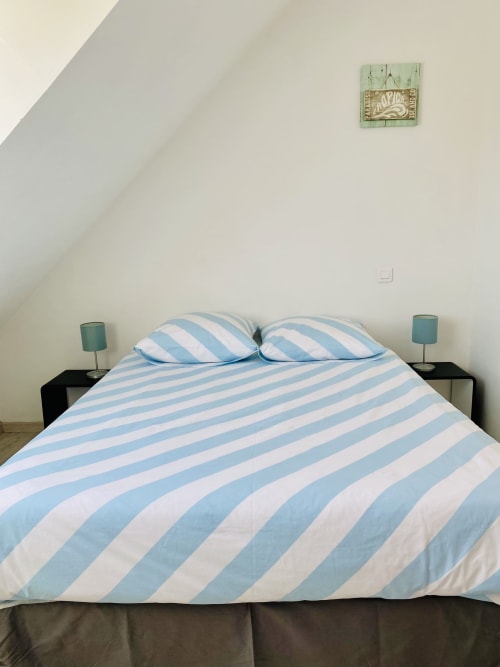 Lit aux rayures bleu et blanc avec deux oreillers dans la chambre Villa Métisse à Île et Villas Groix, Groix France