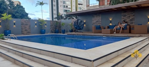 Piscina aquecida do hotel Wellington Rodovalho em Goiânia com área de lazer e parede de tijolos