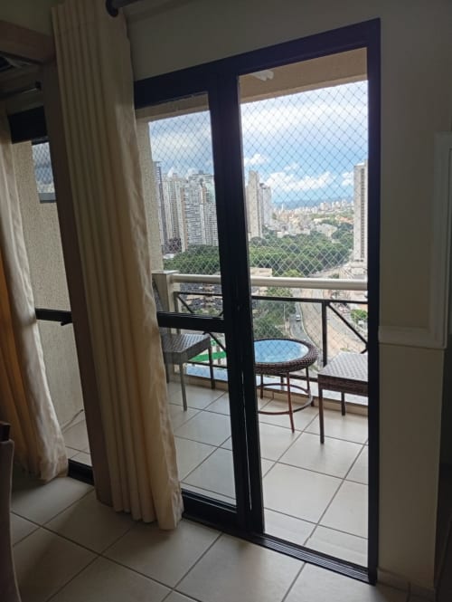 Varanda de apartamento moderno em Wellington Rodovalho em Goiânia com vista do horizonte da cidade, pátio mobiliado e tela de segurança