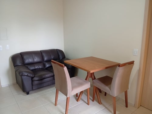 Sala de estar moderna do hotel Wellington Rodovalho em Goiânia com poltrona de couro preta, mesa de jantar de madeira e