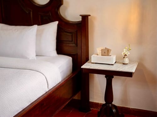 Elegant bedroom at Villa Merida Boutique Hotel with wooden bed, marble nightstand, white linens, and soft ambient lighting in