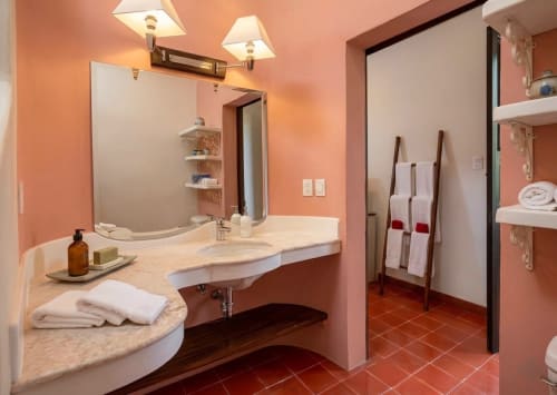 Luxurious bathroom at Villa Merida Boutique Hotel with coral walls, marble vanity, and modern fixtures in Merida