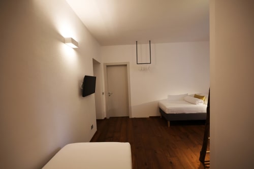 Modern bedroom at La Casa nel Bosco B&B in Somma Lombardo with twin beds, wall-mounted TV, wooden flooring and garden view