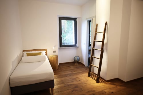 Bright bedroom at La Casa nel Bosco in Somma Lombardo with single bed, wooden ladder, and garden view window