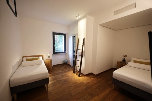 Spacious twin bedroom at La Casa nel Bosco with wooden floors, two single beds, and garden views in Somma Lombardo