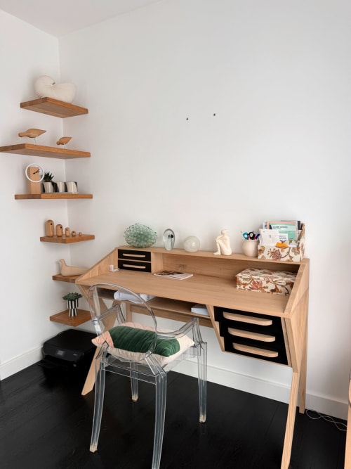 Espace de travail avec bureau en bois moderne, étagères flottantes, chaise transparente et accessoires de bureau organisés à la Villa Eleonore de Maison