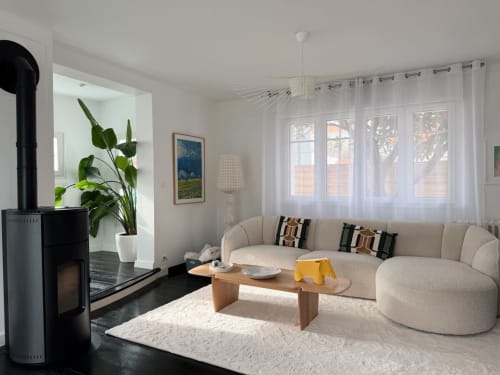 Lumineux salon moderne à la Villa Eleonore avec canapé crème courbé, cheminée et grandes fenêtres sur La Rochelle
