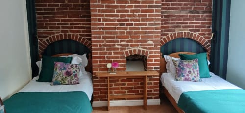 Twin bedroom at Earsham Street House B&B in Bungay with exposed brick arches, teal bedding, and floral pillows.