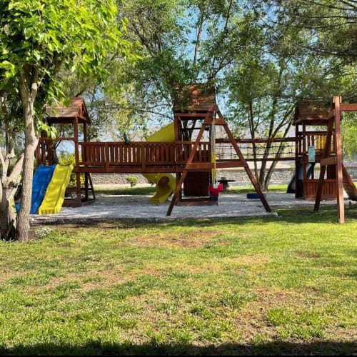 Estructura de juego de madera con toboganes en el frondoso jardín del Hotel El Porvenir, Querétaro