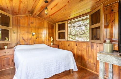 Dormitorio rústico con ropa de cama blanca en la villa Encantadora Casita del Árbol del Hotel El Porvenir en Querétaro, México