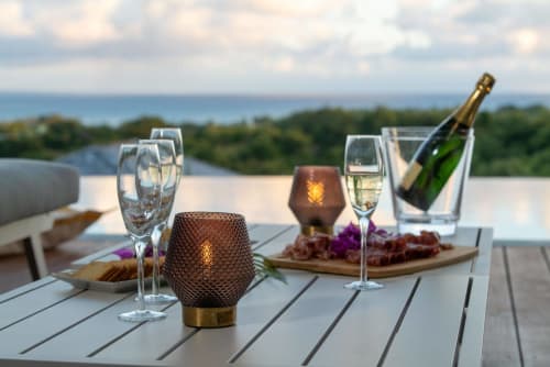 Elegant seaside dining setup at Vista Del Mar with champagne, wine, and appetizers overlooking Sainte-Anne waters