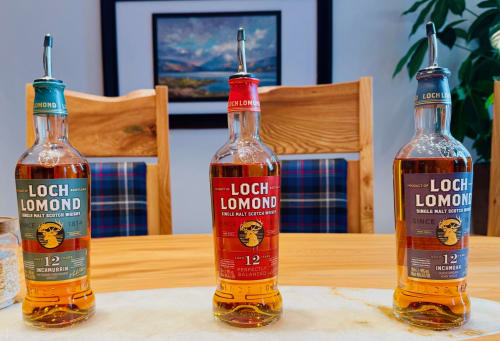 Three Loch Lomond whisky bottles displayed on wooden table at The Corries B&B in Luss