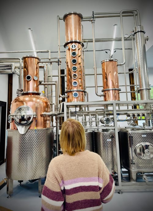 Woman viewing copper distillery equipment at The Corries B&B in Alexandria, Scotland