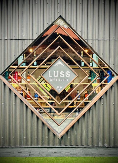 Luss Distillery diamond-shaped storefront display with nested wooden frames and bottles on corrugated metal wall