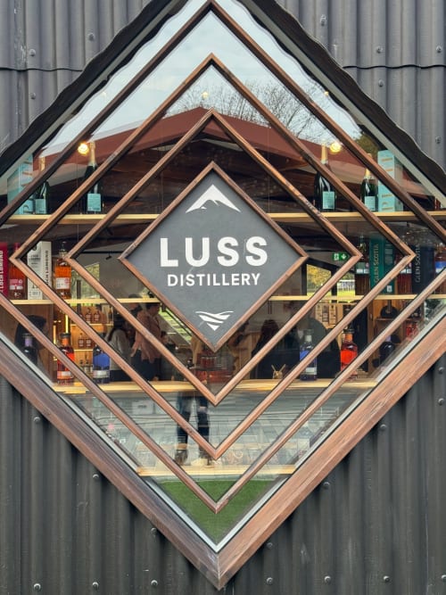 Luss Distillery storefront sign in diamond shape on corrugated metal building, Alexandria