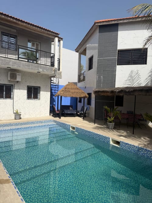 Cour avec piscine de la maison d'hôtes Keur Medzo à Lac Rose, Sénégal, avec bâtiments blancs et gazebo couvert de chaume