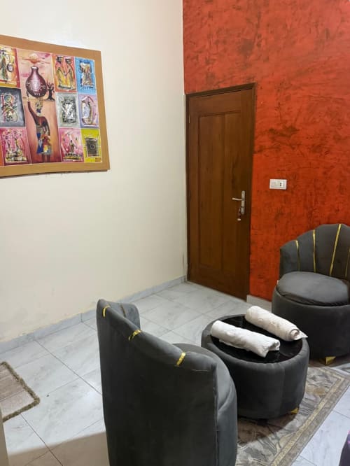 Espace de réception à Keur Medzo avec fauteuils noirs, murs rouge texturé et œuvres de tarot