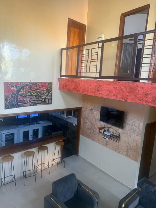 Espace lounge moderne au Keur Medzo Lac Rose avec comptoir de cuisine, bar, télévision et mezzanine à Niaga