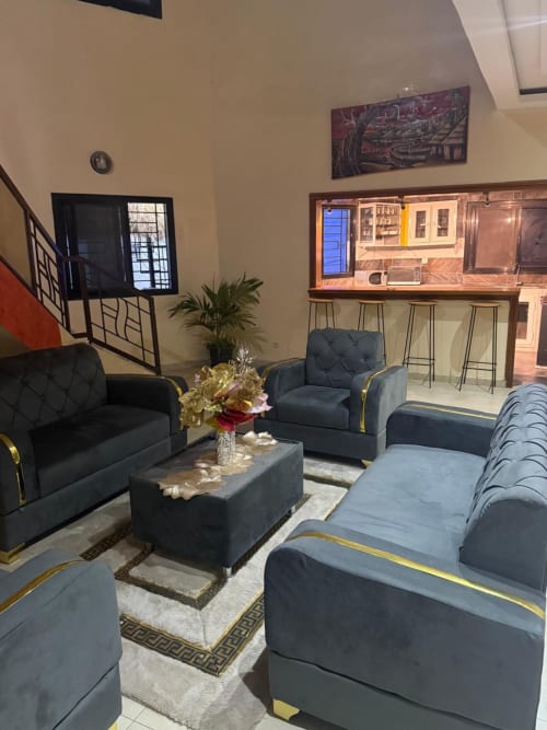 Espace lounge moderne à Keur Medzo avec sièges rembourrés sombre, fleurs décoratives et TV écran plat à Niaga