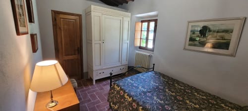 Bedroom at Azienda Agricola Rendola Riding B&B in Montevarchi with bed, white wardrobe, lamp, and terracotta flooring