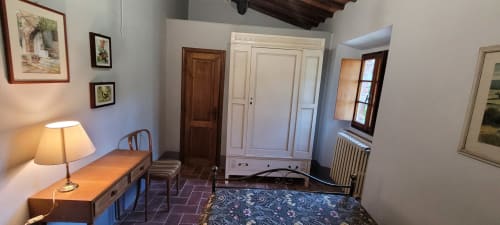 Rustic Italian room with terracotta floors, wooden beams, period furniture, and white wardrobe at Rendola farm B&B