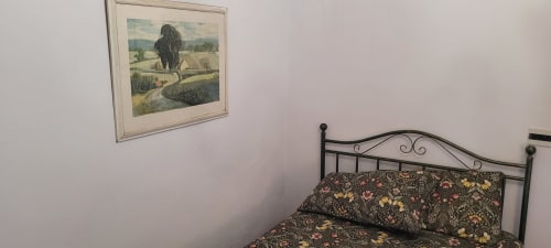Cozy bedroom at Azienda Agricola Rendola Riding with wrought iron bed, floral bedding, and rustic landscape artwork