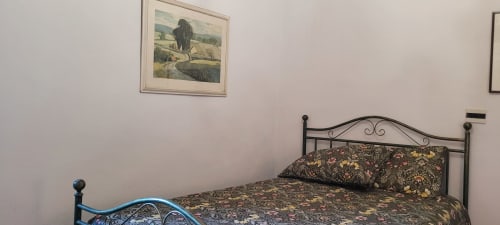 Cozy bedroom at Azienda Agricola Rendola with wrought iron bed and countryside artwork, Montevarchi