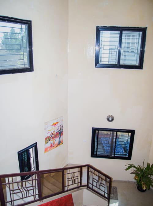 Escalier de la maison d'hôtes Keur Medzo Lac Rose avec fenêtres, œuvres d'art et rampes décoratives
