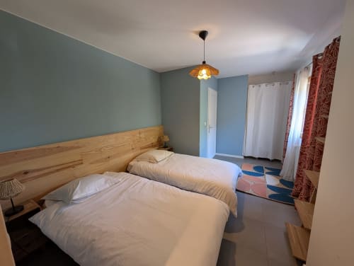 Twin bedroom with wooden headboards at Domaine de Pelican villa in Gignac, France, featuring blue walls and garden view