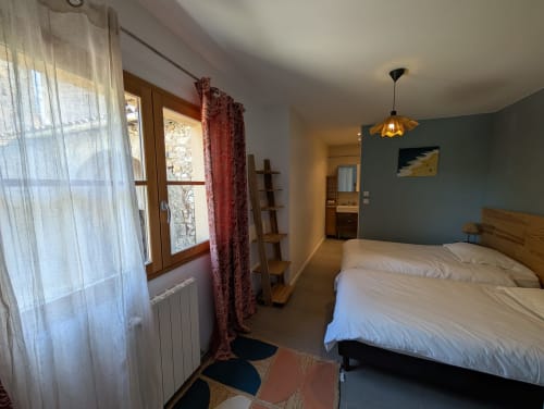 Spacious bedroom in Gîte Ramonétage villa at Domaine de Pelican, Gignac, with garden view, wooden bed, blue accent wall, and