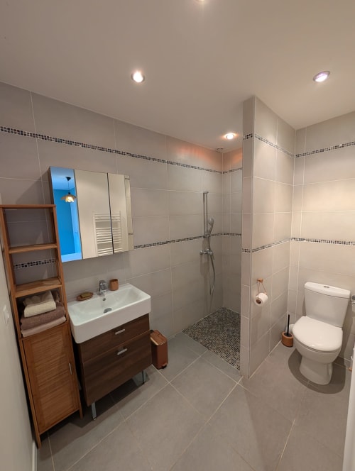 Modern bathroom in Gîte Ramonétage villa at Domaine de Pelican, featuring tiled walls, walk-in shower, vanity, toilet, and