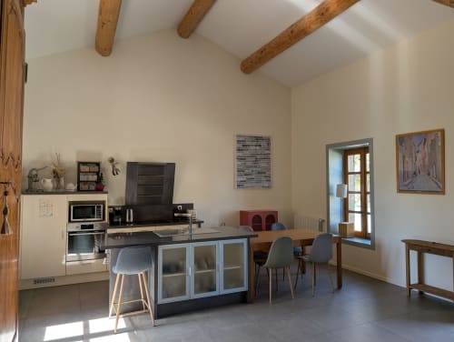 Modern kitchen-dining area at Gîte Ramonétage villa in Gignac with exposed beams, island counters, and garden view doors