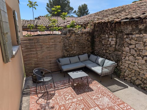 Outdoor patio seating area at Domaine de Pelican villa in Gignac with stone walls, lounge furniture, and shaded garden views