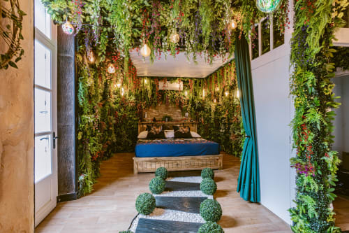 La Jungle Room aux Gîtes De Dordogne : des murs de plantes vertes luxuriantes encadrent un lit en bois avec une literie bleue dans cette chambre au thème botanique